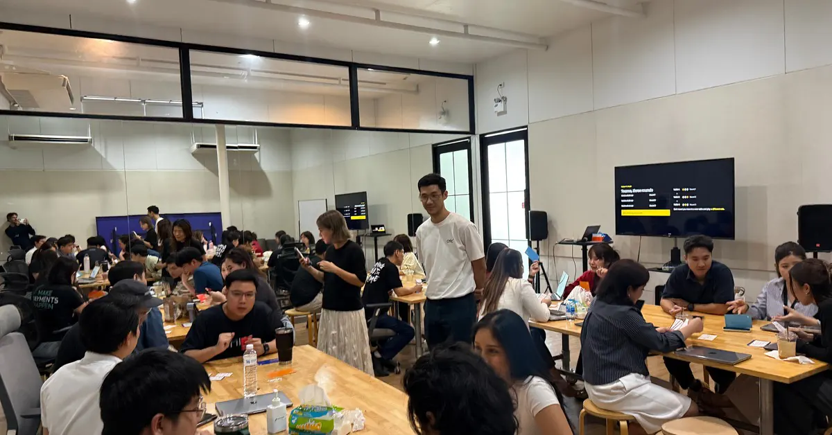A full room of people playing Client Quest at several tables at once